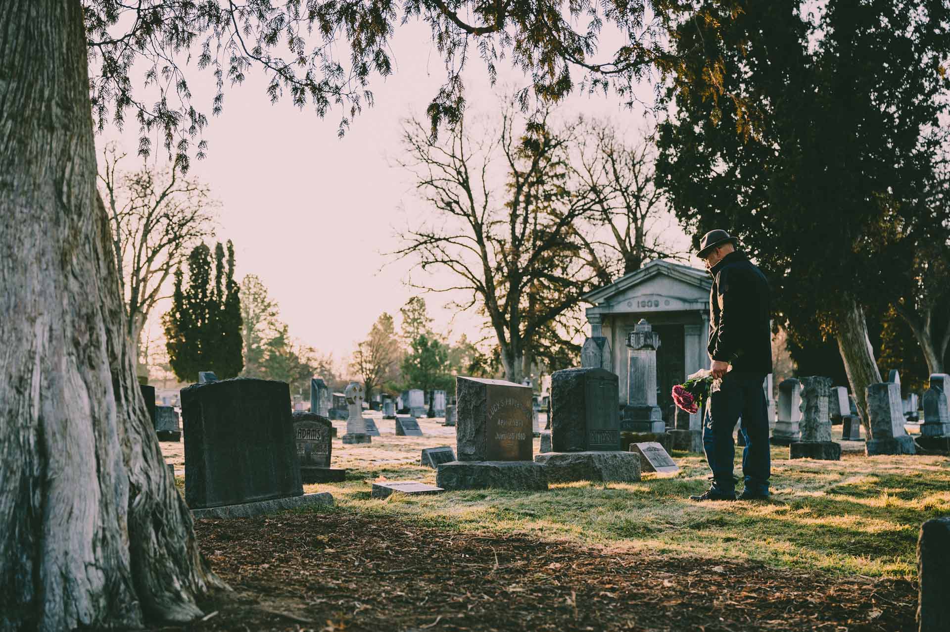 Man walking up to a tombstone